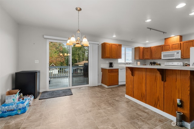 kitchen featuring white appliances, a notable chandelier, decorative light fixtures, and a kitchen bar