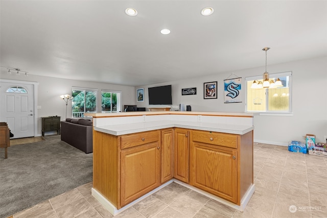 kitchen featuring light carpet, a chandelier, decorative light fixtures, and a kitchen island