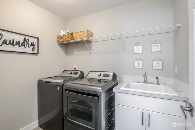 clothes washing area featuring cabinets, sink, and washer and dryer