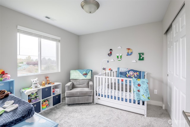 carpeted bedroom with a closet and a crib