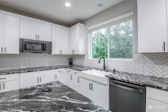 kitchen featuring white cabinets, appliances with stainless steel finishes, tasteful backsplash, and dark stone counters