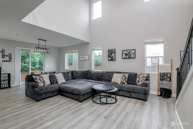 living room featuring a wealth of natural light, a towering ceiling, and light hardwood / wood-style flooring