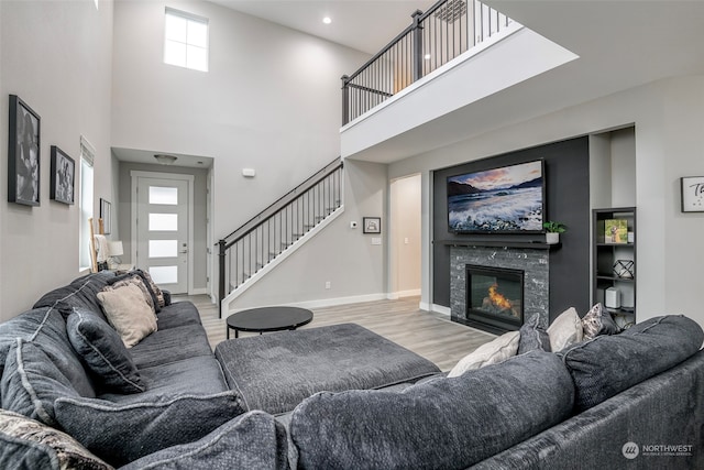 living room with a fireplace, a high ceiling, and light wood-type flooring