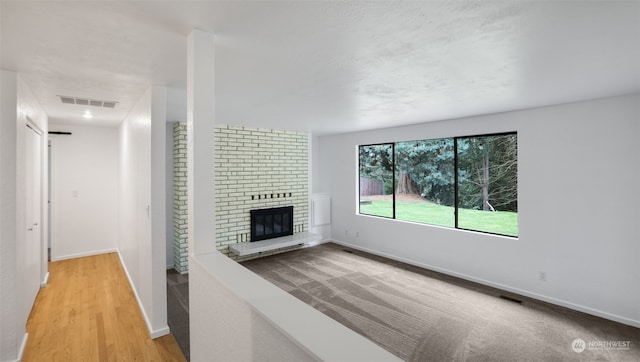 unfurnished living room with a brick fireplace and light hardwood / wood-style floors