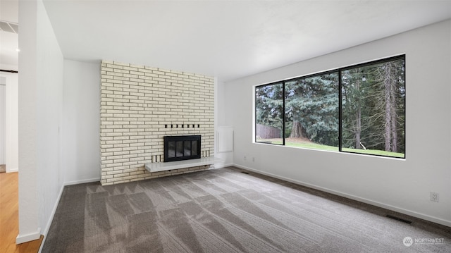 unfurnished living room with a fireplace, a barn door, and carpet flooring