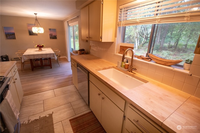 kitchen featuring pendant lighting, plenty of natural light, dishwasher, and light hardwood / wood-style flooring