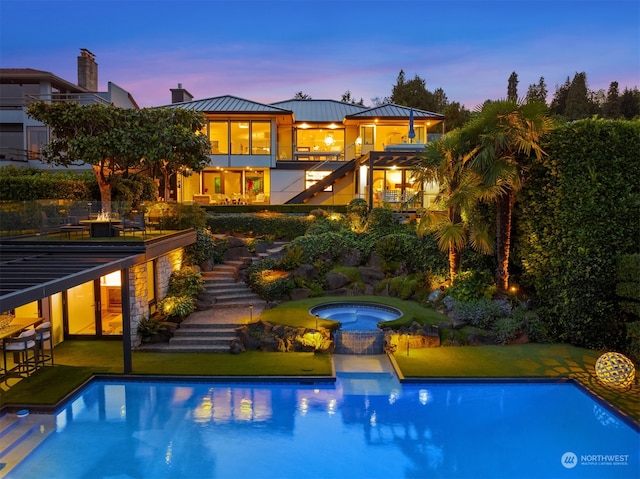 pool at dusk with an in ground hot tub and a yard