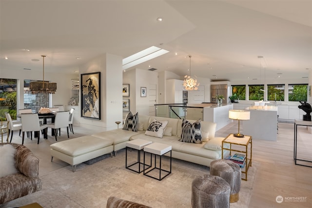 living room with light hardwood / wood-style floors, vaulted ceiling, and a notable chandelier