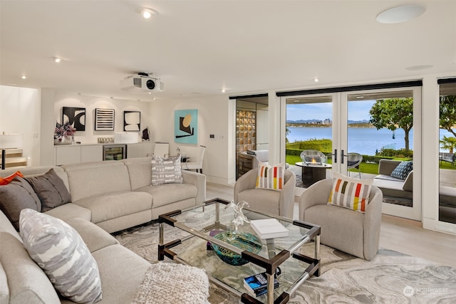 living room featuring french doors, light wood-type flooring, and a water view