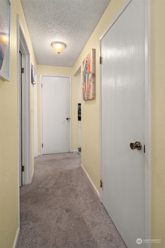 hallway featuring a textured ceiling and light carpet