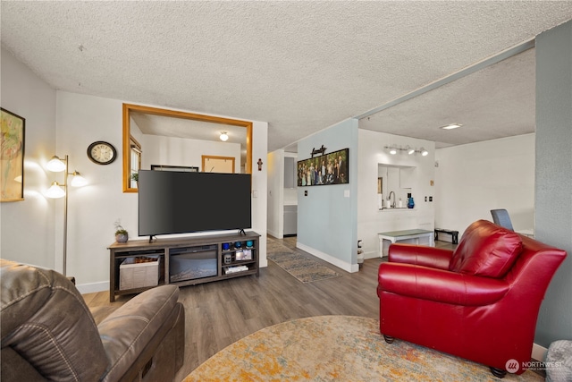 living room with hardwood / wood-style floors, sink, and a textured ceiling