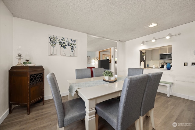 dining area featuring light hardwood / wood-style floors, sink, and a textured ceiling