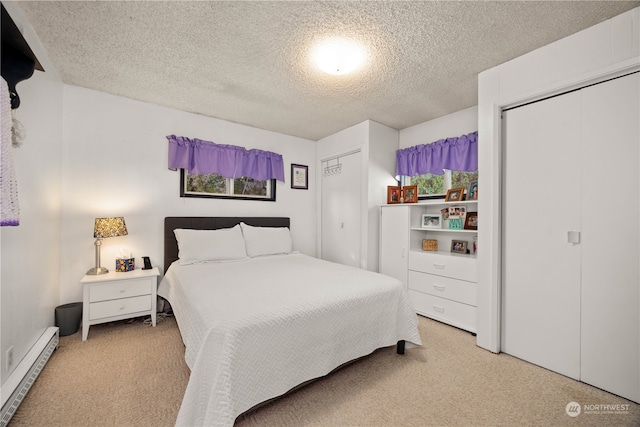 bedroom with carpet floors, a closet, baseboard heating, and a textured ceiling