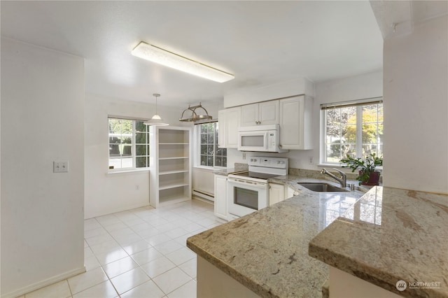 kitchen with white appliances, kitchen peninsula, sink, and a wealth of natural light