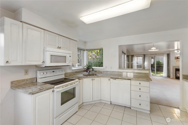 kitchen featuring white appliances, sink, hanging light fixtures, white cabinetry, and light colored carpet