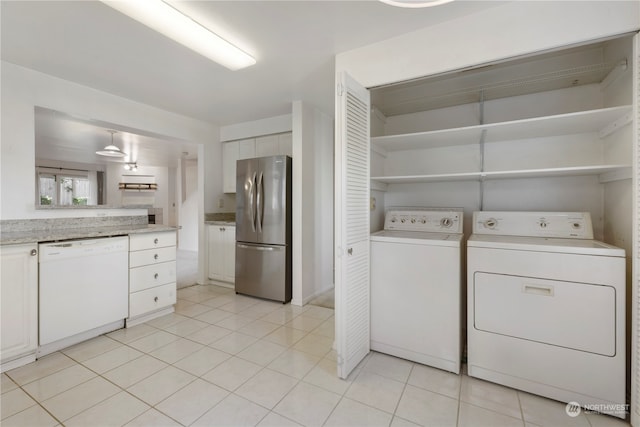 clothes washing area with independent washer and dryer and light tile patterned floors