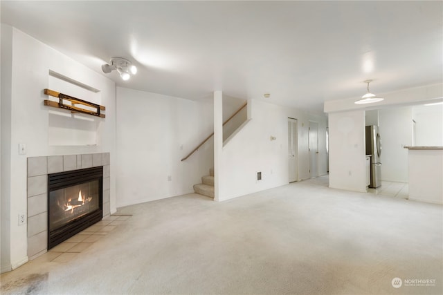 unfurnished living room featuring light colored carpet and a tiled fireplace