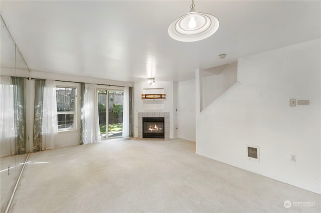 unfurnished living room featuring light colored carpet and a tiled fireplace