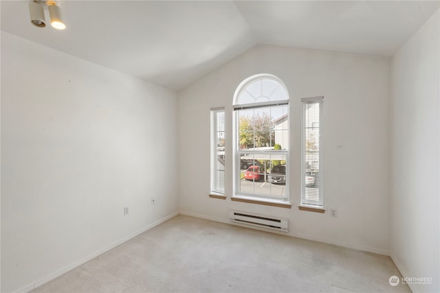 carpeted empty room with vaulted ceiling and a baseboard heating unit