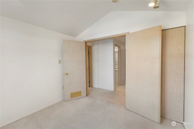 carpeted spare room with vaulted ceiling