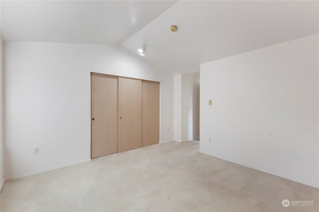 unfurnished bedroom featuring light colored carpet, a closet, and vaulted ceiling