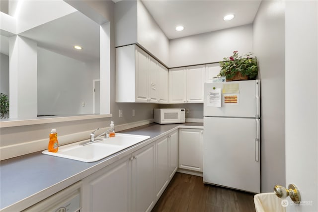 kitchen featuring white appliances, dark hardwood / wood-style floors, white cabinets, and sink