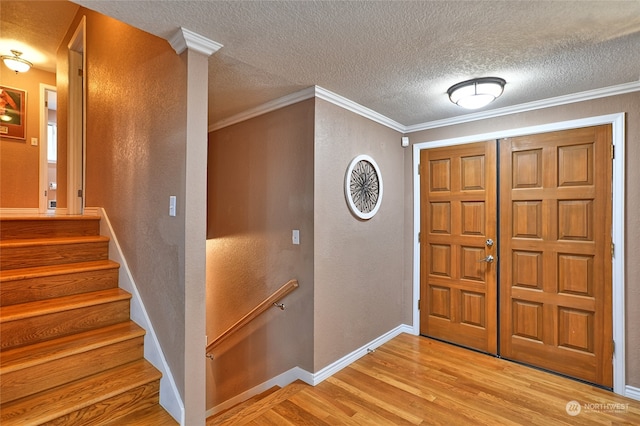 entryway featuring light hardwood / wood-style floors, crown molding, and a textured ceiling