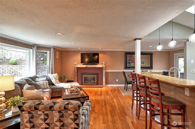 living room with ornamental molding, a textured ceiling, light wood-type flooring, and a fireplace