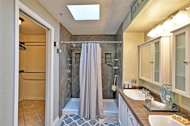 bathroom with a textured ceiling, walk in shower, a skylight, vanity, and tile patterned flooring