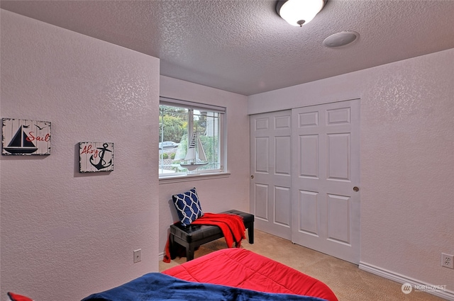 carpeted bedroom with a textured ceiling and a closet