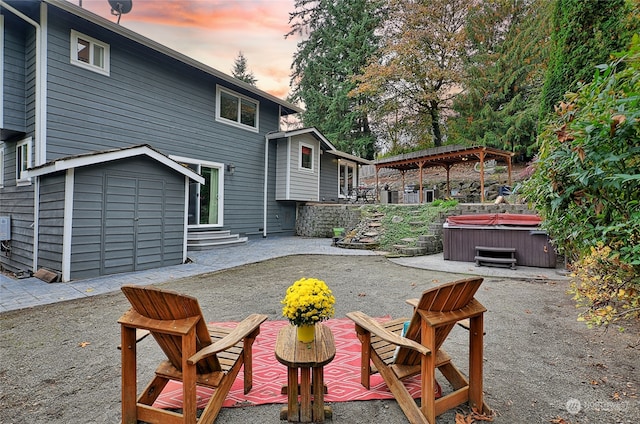 patio terrace at dusk featuring a hot tub