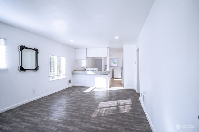 unfurnished living room featuring sink, dark wood-type flooring, and washer / dryer