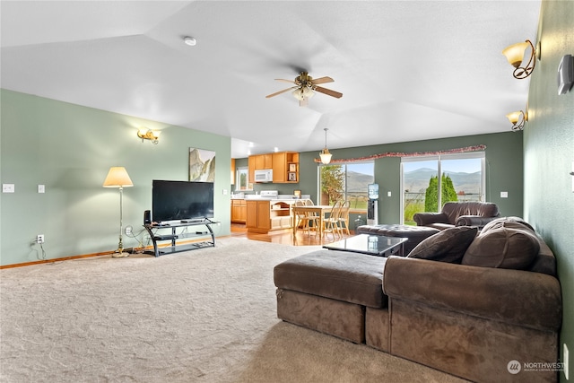 living room with ceiling fan, vaulted ceiling, and light colored carpet