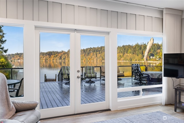 doorway with french doors, light wood-type flooring, and a water view