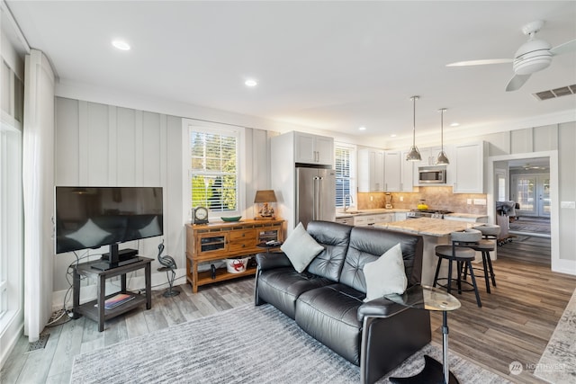 living room with ceiling fan, ornamental molding, and light hardwood / wood-style flooring