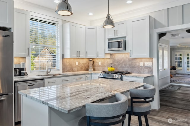 kitchen with white cabinetry, appliances with stainless steel finishes, dark hardwood / wood-style floors, sink, and a breakfast bar