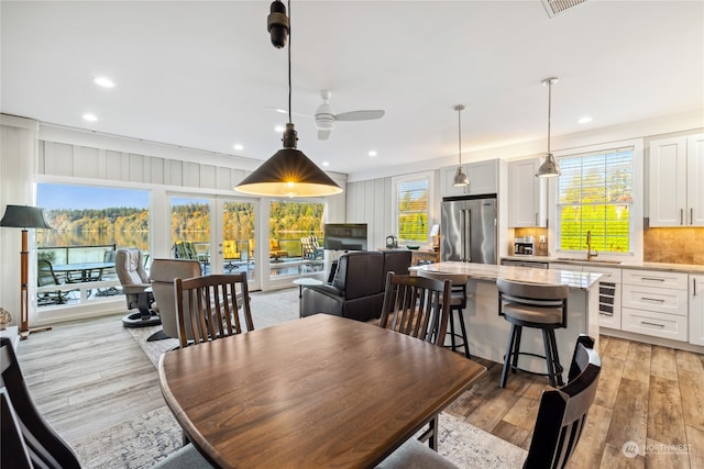 dining room with sink, ornamental molding, ceiling fan, light hardwood / wood-style flooring, and french doors