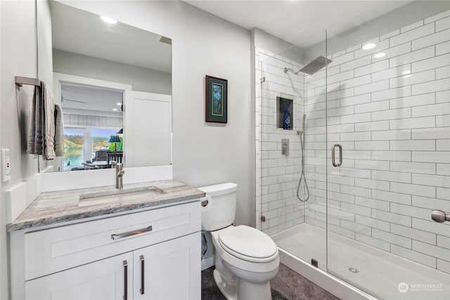 bathroom with toilet, vanity, and a shower with shower door