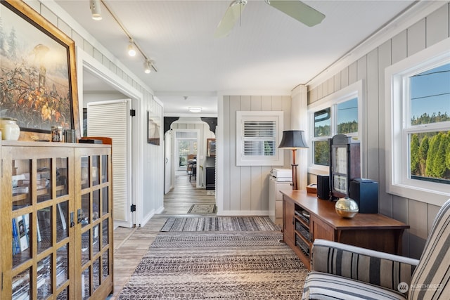 interior space with track lighting, wooden walls, wood-type flooring, and ornamental molding