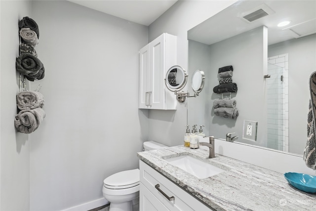 bathroom with toilet, vanity, and a shower with shower door