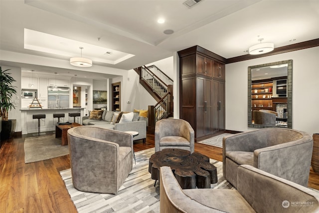 living room with a fireplace, a tray ceiling, and light hardwood / wood-style flooring