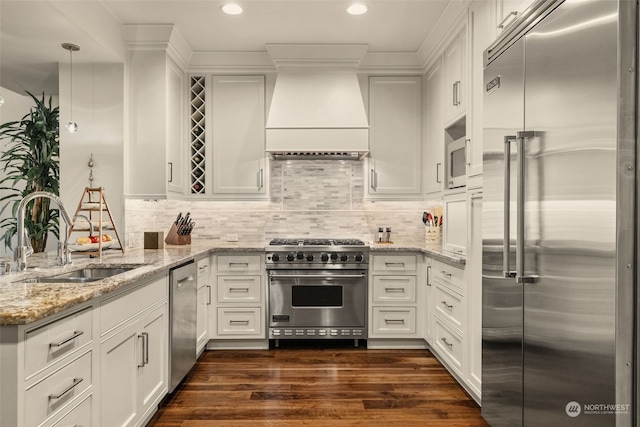 kitchen featuring sink, high quality appliances, custom range hood, light stone countertops, and white cabinets