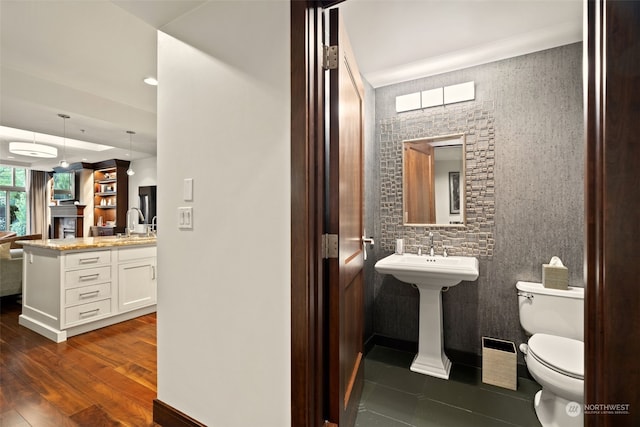 bathroom featuring hardwood / wood-style floors, a wall unit AC, sink, and toilet