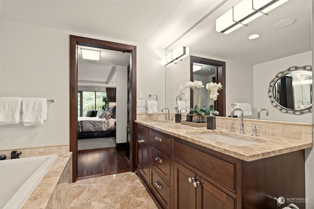 bathroom featuring tiled tub and vanity