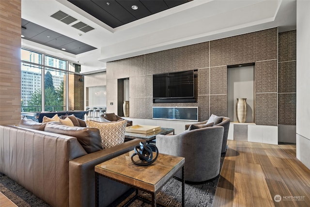 living room featuring wood-type flooring, a raised ceiling, and expansive windows