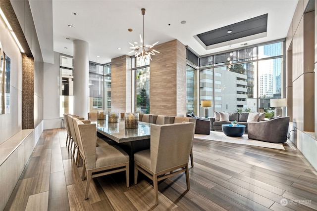 dining space with a notable chandelier, a tray ceiling, light hardwood / wood-style flooring, and expansive windows