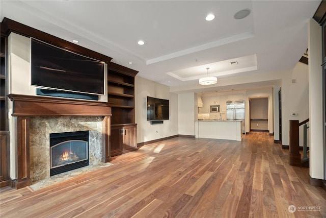 unfurnished living room with a raised ceiling, wood-type flooring, and a fireplace