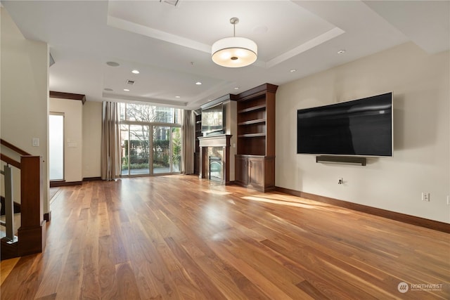 unfurnished living room featuring hardwood / wood-style floors and a tray ceiling