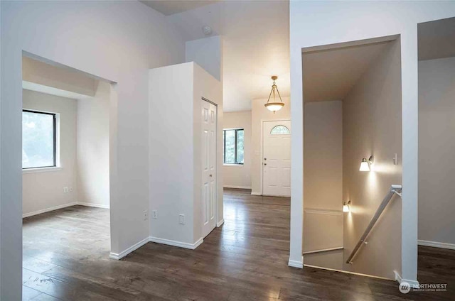 hall with a healthy amount of sunlight, vaulted ceiling, and dark hardwood / wood-style flooring