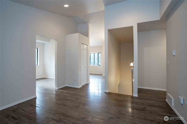 empty room with high vaulted ceiling and dark hardwood / wood-style flooring